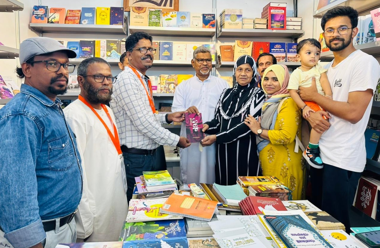 Abdul Azeez receives the book 'Malu' from Haroon Kakkad at the Sharjah Book Festival